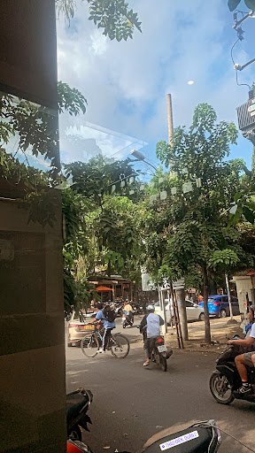 The image captures a bustling street scene in Thao Dien, Saigon. It shows various modes of transportation including bicycles and motorcycles on the ro