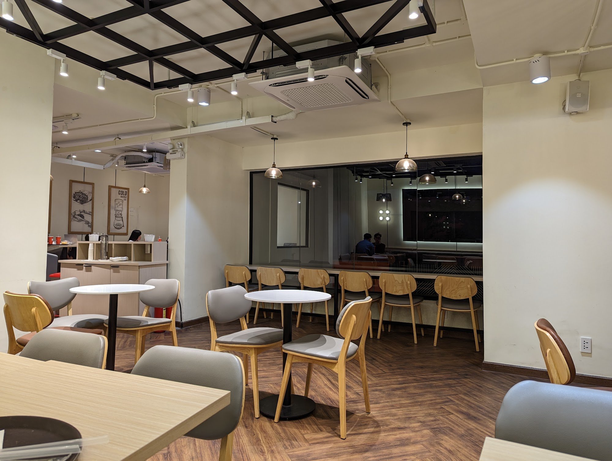 The image shows an interior view of a modern café or restaurant in Thao Dien, Saigon. The space is well-lit with both overhead and pendant lighting fi