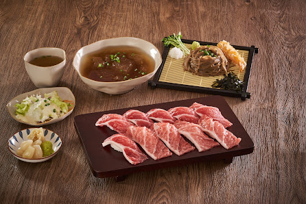 The image shows a traditional Japanese meal consisting of sliced raw beef on a wooden tray accompanied by various side dishes including miso soup, pic
