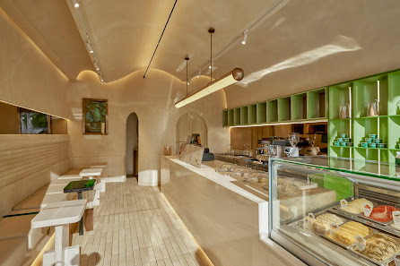 This image depicts an interior view of a modern coffee shop or cafe in Thao Dien, Saigon. The space features warm lighting and earthy tones with green