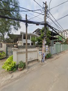 The image shows a street view of an urban area with buildings under construction and some greenery along the roadside.