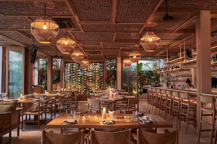 The image depicts the interior of a restaurant located in Thao Dien, Saigon. It features wooden tables and chairs arranged throughout the space, with 
