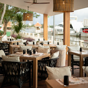 The image depicts an elegant dining area within a restaurant located in Thao Dien, Saigon. The space features modern decor with wooden tables and chai