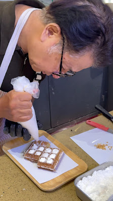 A dessert with white cream and chocolate squares