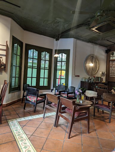 The image depicts an interior space that appears to be a cozy café or restaurant in Thao Dien, Saigon. The room features terracotta tiled flooring and