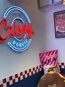 The image shows a part of an interior space featuring a neon sign that reads 'Crispy Donuts' with the establishment's founding year, which is illumina