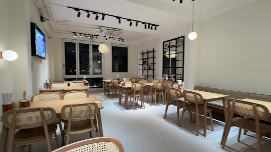 The image shows an interior view of a modern restaurant or café in Thao Dien, Saigon. The space is well-lit with track lighting and features wooden ta