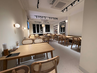 The image shows an interior view of a modern cafe or restaurant in Thao Dien, Saigon. The space is well-lit with track lighting and features wooden ta