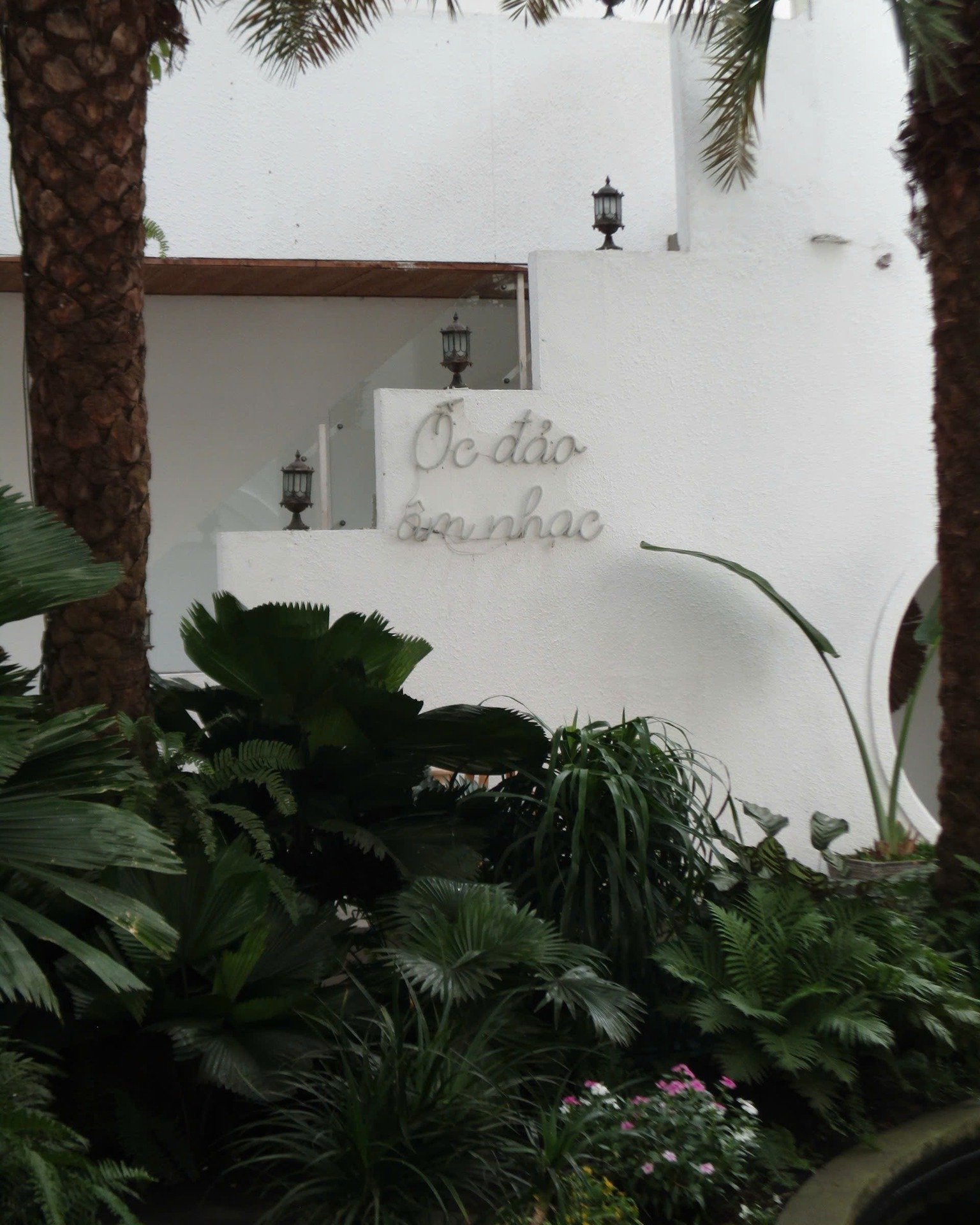 The image shows a white wall of what appears to be an exterior building in Thao Dien, Saigon. The wall has decorative elements including two lantern-s