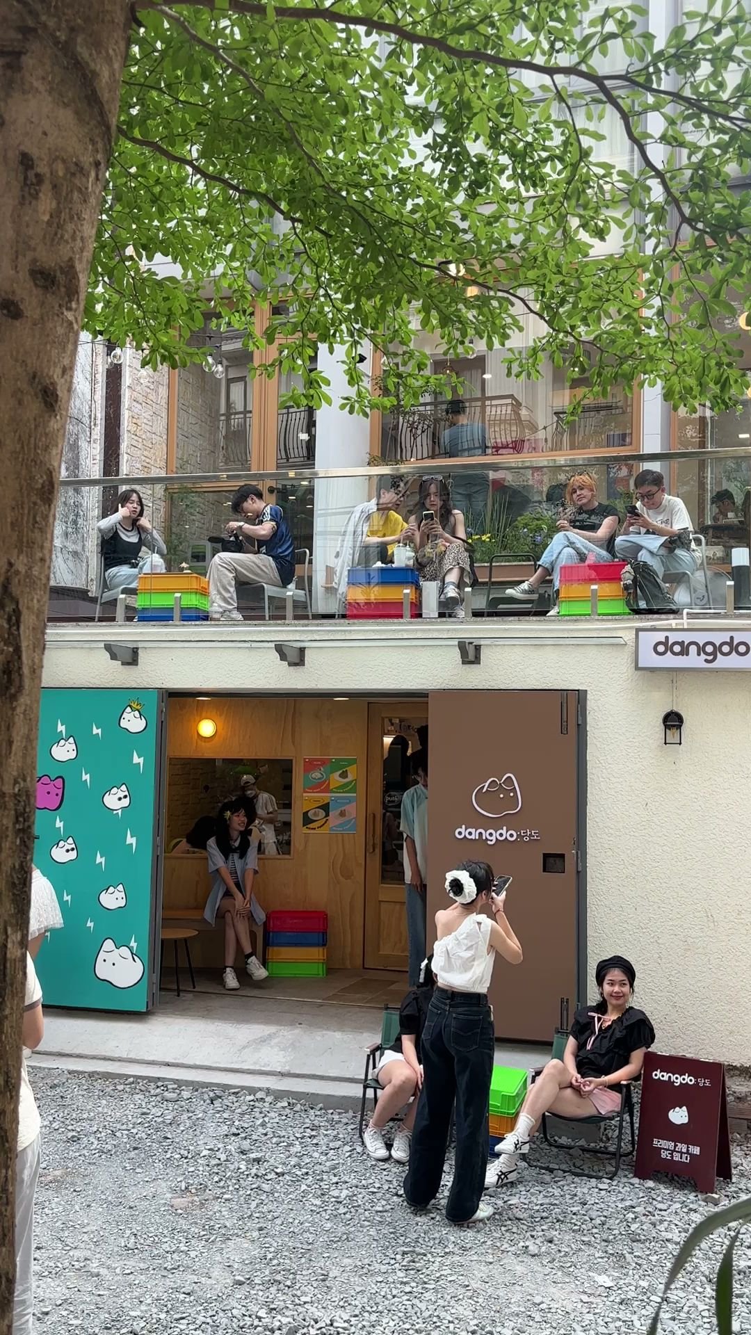 The image captures an outdoor seating area of a café named 'dangdo,' which is decorated with colorful blocks and has patrons enjoying their time on di