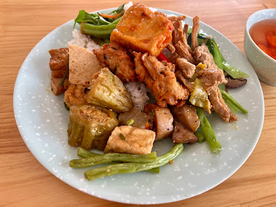 A plate of stir-fried vegetables and tofu served on a bed of rice.