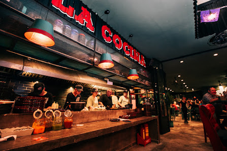 The image depicts the interior of a cocktail bar named "LA COCKTAIL" in Thao Dien, Saigon. It features a bar counter with staff preparing drinks, hang