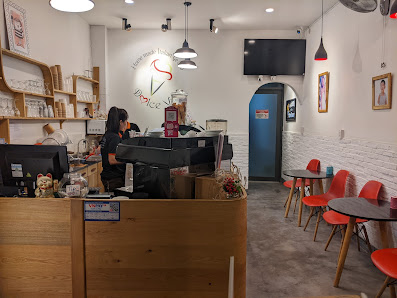 The image shows an interior view of a cafe or restaurant in Thao Dien, Saigon. The space is modern with white walls and red accents from the chairs to