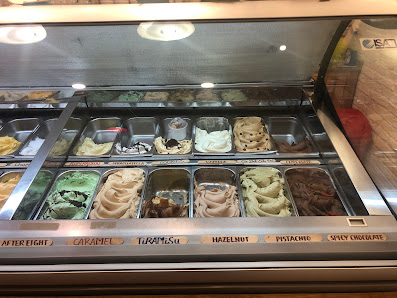 A display case in a dessert shop showcasing various flavors of ice cream and other frozen treats.
