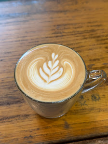 A close-up of a latte art on top of coffee in a glass cup placed on a wooden surface.