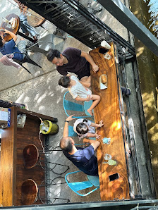 The image shows an aerial view of a group of people sitting at a wooden table outdoors in what appears to be a cafe or restaurant setting near Thao Di