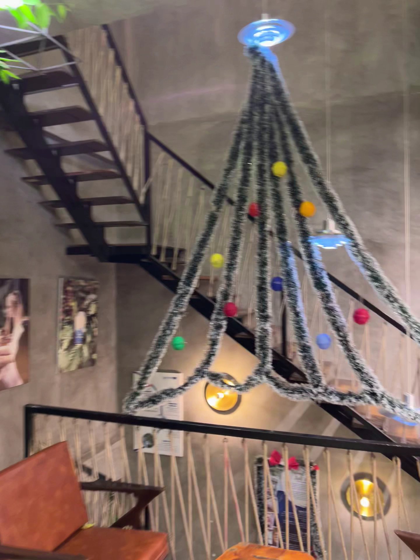 The image depicts the interior of a venue in Thao Dien, Saigon, featuring a large, triangular Christmas tree structure made of black-and-white tinsel 