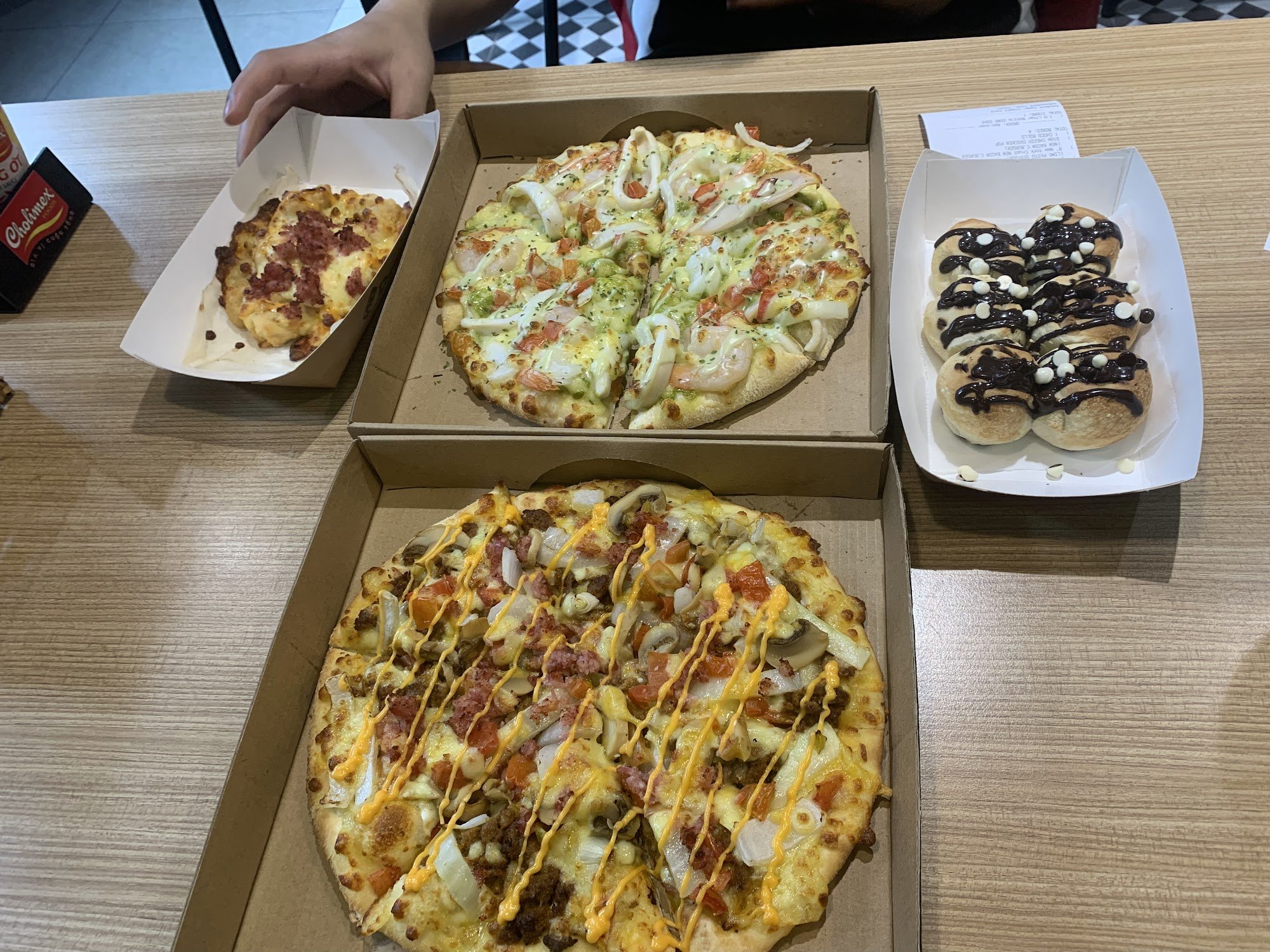 [{"name": "Pizza with bacon and cheese", "cuisine_tags": ["Italian"]}, {"name": "Pizza with shrimp, onions, and possibly chicken or sausage", "cuisine_tags": ["Italian"]}, {"name": "Chocolate drizzled bread rolls", "presentation": "takeaway"}]