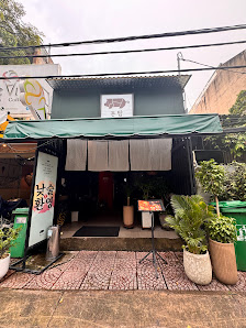 The image depicts the exterior of a casual eatery or café in Thao Dien, Saigon. It features a green awning over the entrance, a tiled walkway leading 