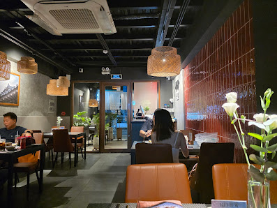 The image depicts an indoor dining area of a restaurant or cafe in Thao Dien, Saigon. The interior features modern decor with dark tones and red accen
