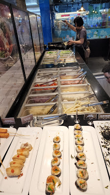 The image depicts the interior of a sushi restaurant in Thao Dien, Saigon. A long sushi counter with multiple sections is visible, featuring various s