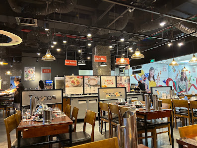 The image depicts the interior of a modern restaurant in Thao Dien, Saigon. It features wooden tables and chairs, stainless steel containers on tables