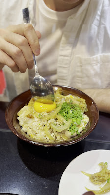 A close-up of a plate containing what appears to be an omelette or scrambled eggs with vegetables and possibly some herbs on top, served in a dark bro