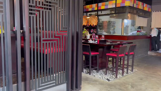 Interior of a modern restaurant in Thao Dien, Saigon. Features a geometric metal partition with vertical slats, red cushioned high stools with dark fr