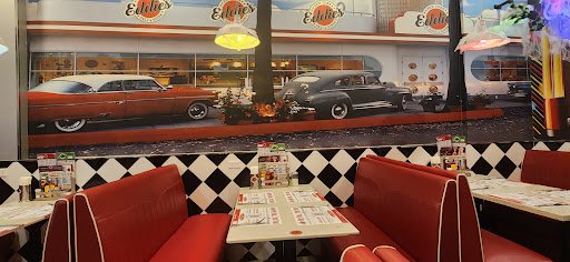 The image depicts the interior of a restaurant in Thao Dien, Saigon. It features red vinyl booths with white piping, black-and-white checkered wall ti