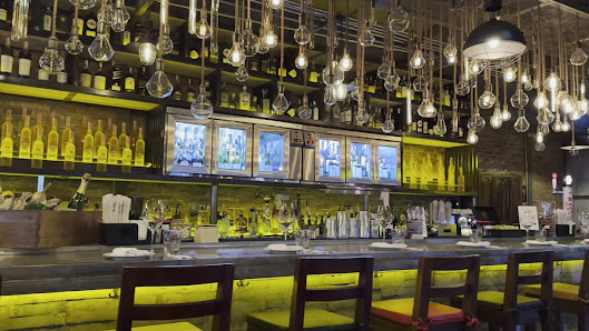 The image shows a well-lit bar area in an upscale establishment named Thao Dien, Saigon. The counter is adorned with numerous hanging wine glasses and