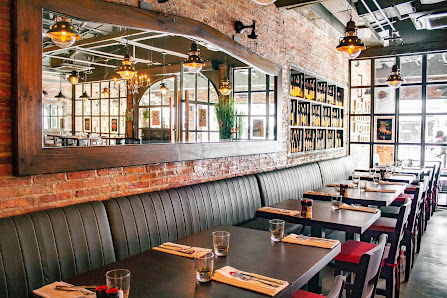 The image depicts an interior view of a restaurant or cafe in Thao Dien, Saigon. The space features exposed brick walls and large windows that allow n