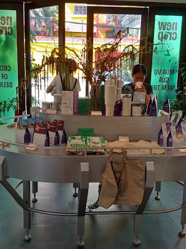 The image shows an interior view of a coffee shop or cafe counter area where products are displayed for sale and staff is attending to customers.