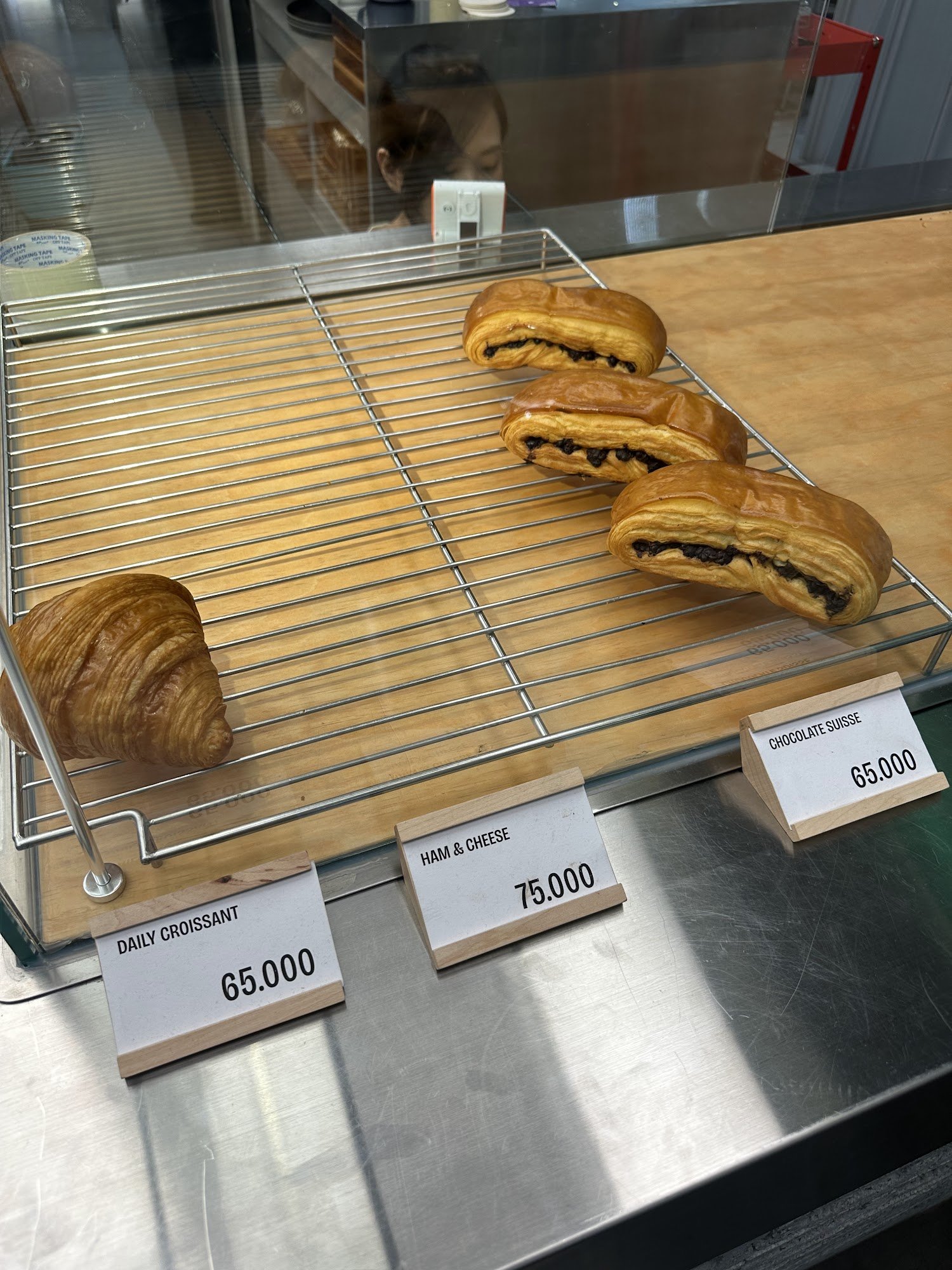 A display case in a bakery or café showcasing various pastries and their prices.