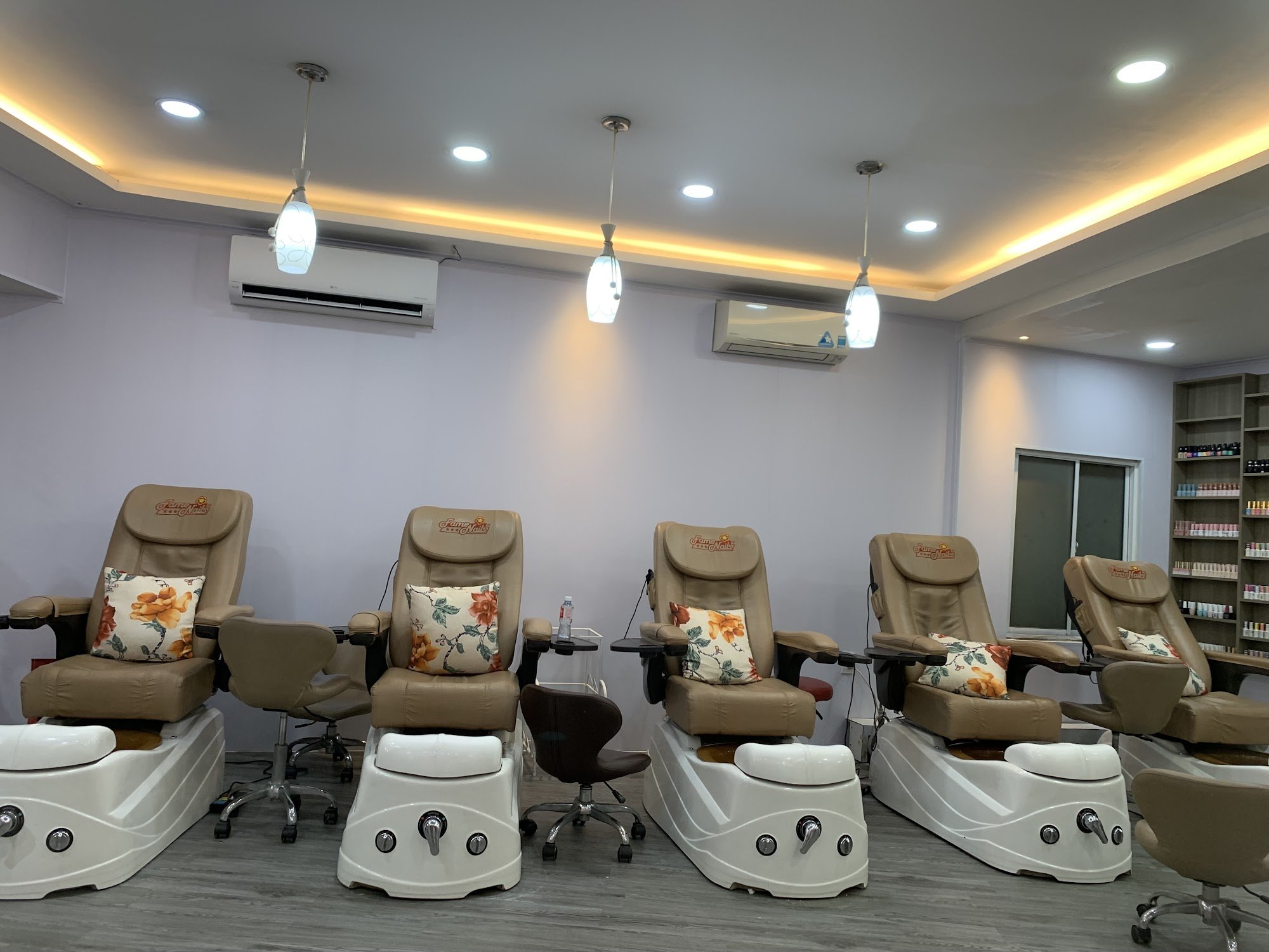The image shows a well-lit interior of what appears to be a nail salon or spa with multiple pedicure chairs arranged in rows, each equipped with foot 