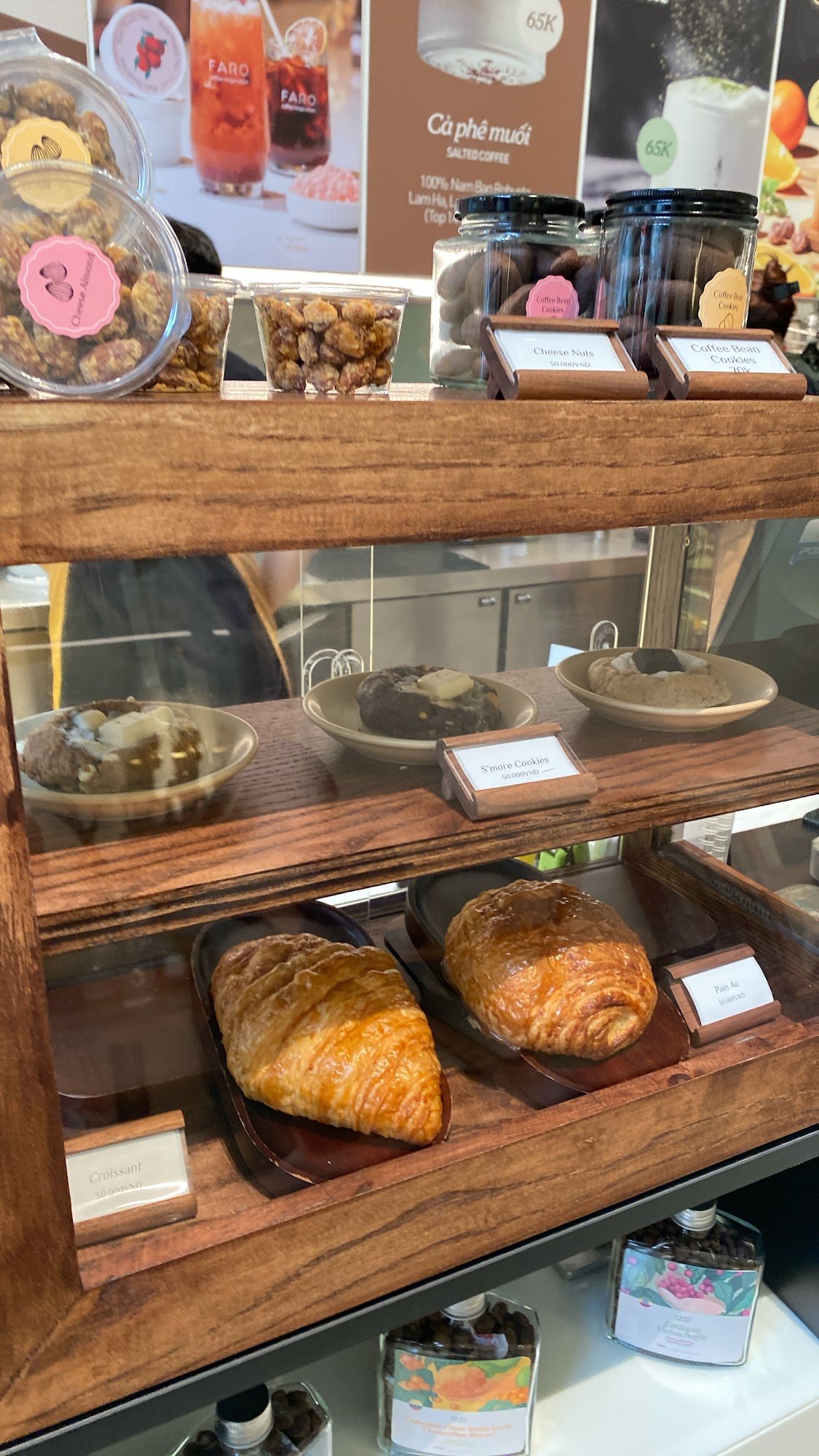 The image shows a display case in what appears to be a café or bakery setting at Thao Dien, Saigon. The case contains various baked goods and snacks s