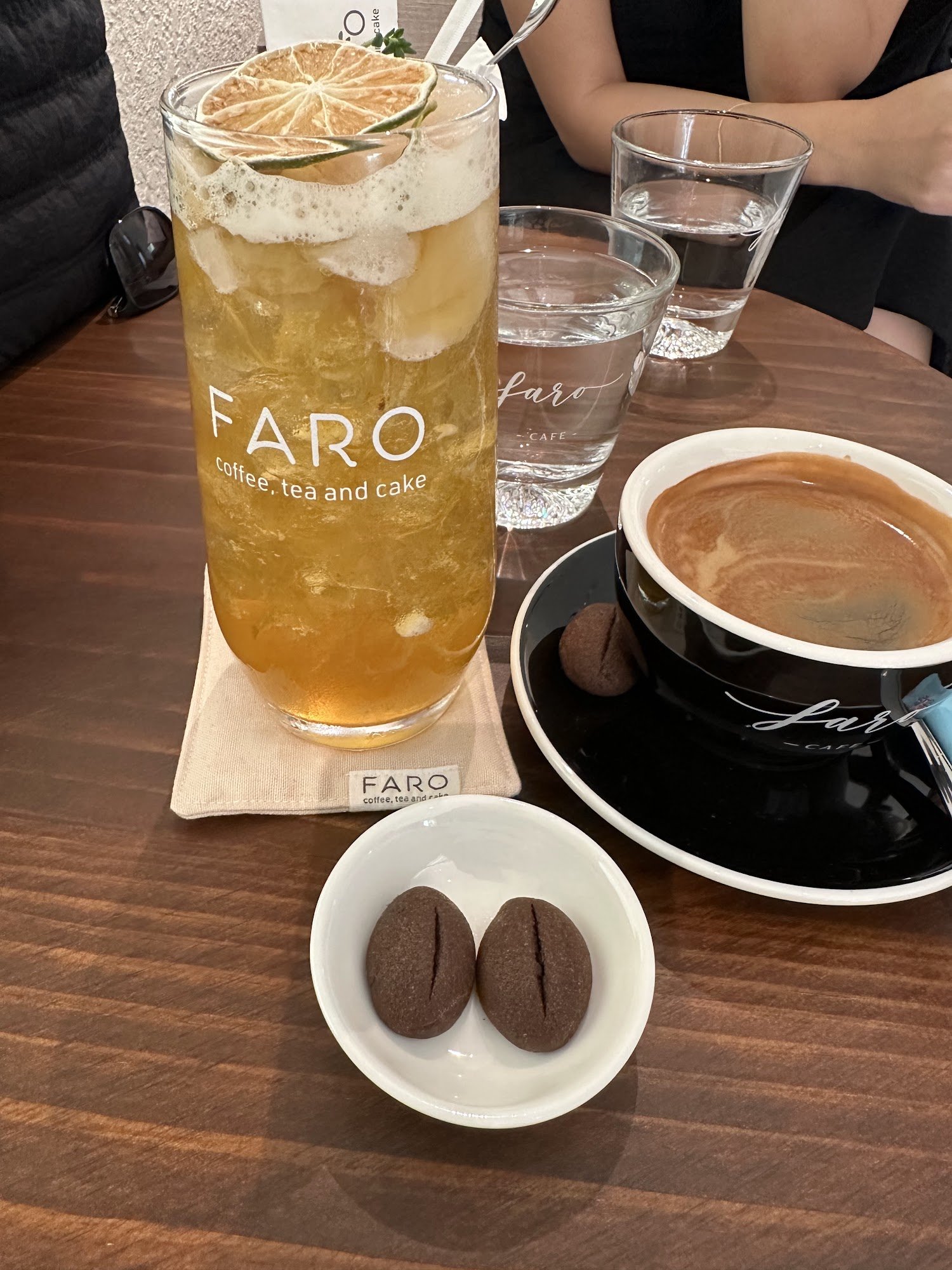 A table setting in a cafe named 'FARO', which offers coffee, tea and cake as indicated by the branding on the glassware and plates.