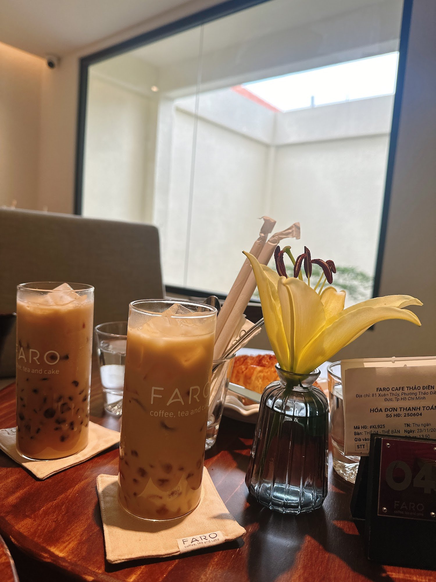 The image shows a table setting in an indoor cafe environment at Thao Dien, Saigon with two glasses of bubble tea and another glass labeled 'FAR' whic