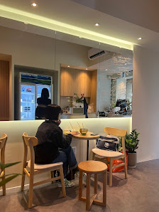The image shows an indoor setting of a modern cafe or restaurant in Thao Dien, Saigon. A person is seated at a table with drinks and food items on the