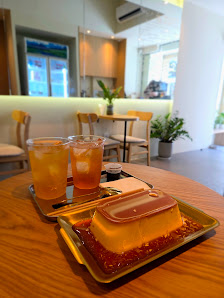 The image shows a modern cafe interior featuring wooden furniture and plants in the background.