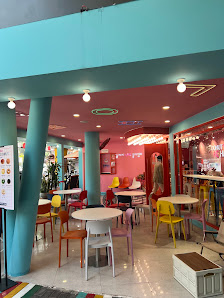 The image shows an interior view of a colorful restaurant or cafe in Thao Dien, Saigon. The space is vibrant with pink and blue walls, various colored