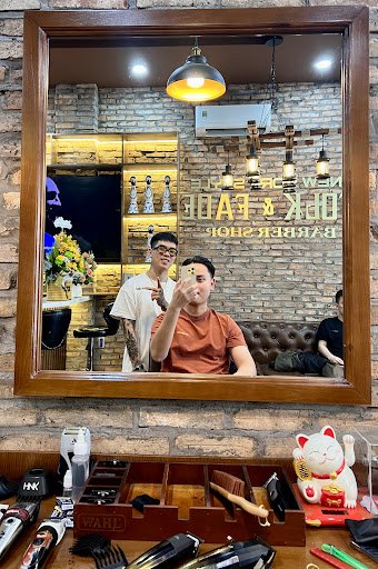 The image shows an interior view of a barber shop named 'Old K Cafe Barber Shop'. The reflection in the mirror captures two individuals, one standing 