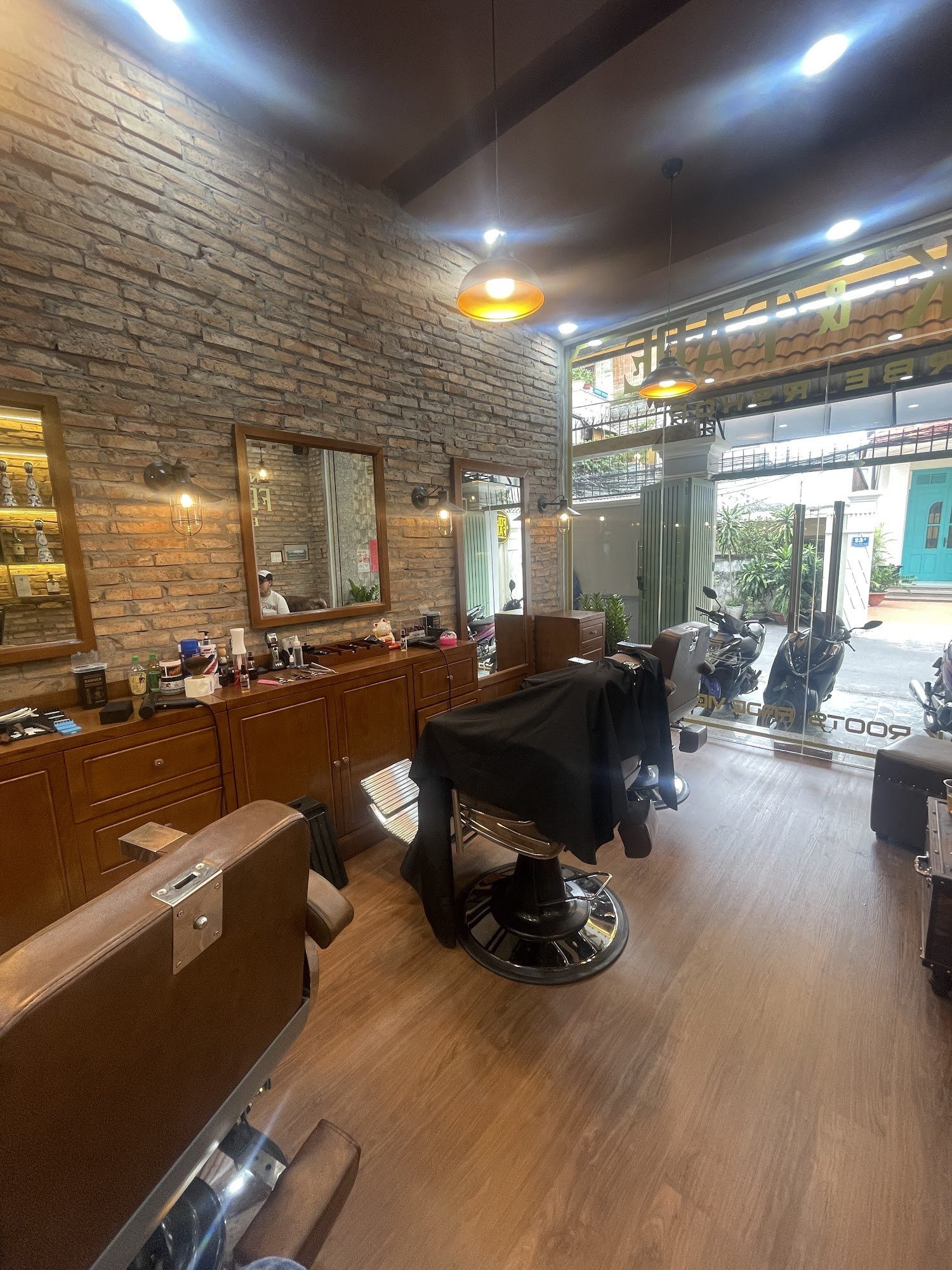 The image shows an interior view of a barber shop or hair salon located in Thao Dien, Saigon. The establishment has a rustic and modern aesthetic with