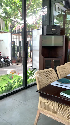 The image depicts the interior of a venue in Thao Dien, Saigon, featuring a modern café or meeting space. Inside, there's a wooden table with woven ch