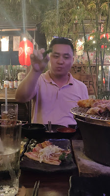 A person is sitting at a table in an outdoor dining area of Thao Dien, Saigon. They are holding up a lit candle and there's another dish on the table 