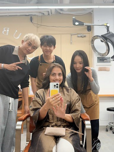 A group of people posing for a photo in what appears to be an interior setting that resembles a beauty salon or hair studio, with modern and clean des
