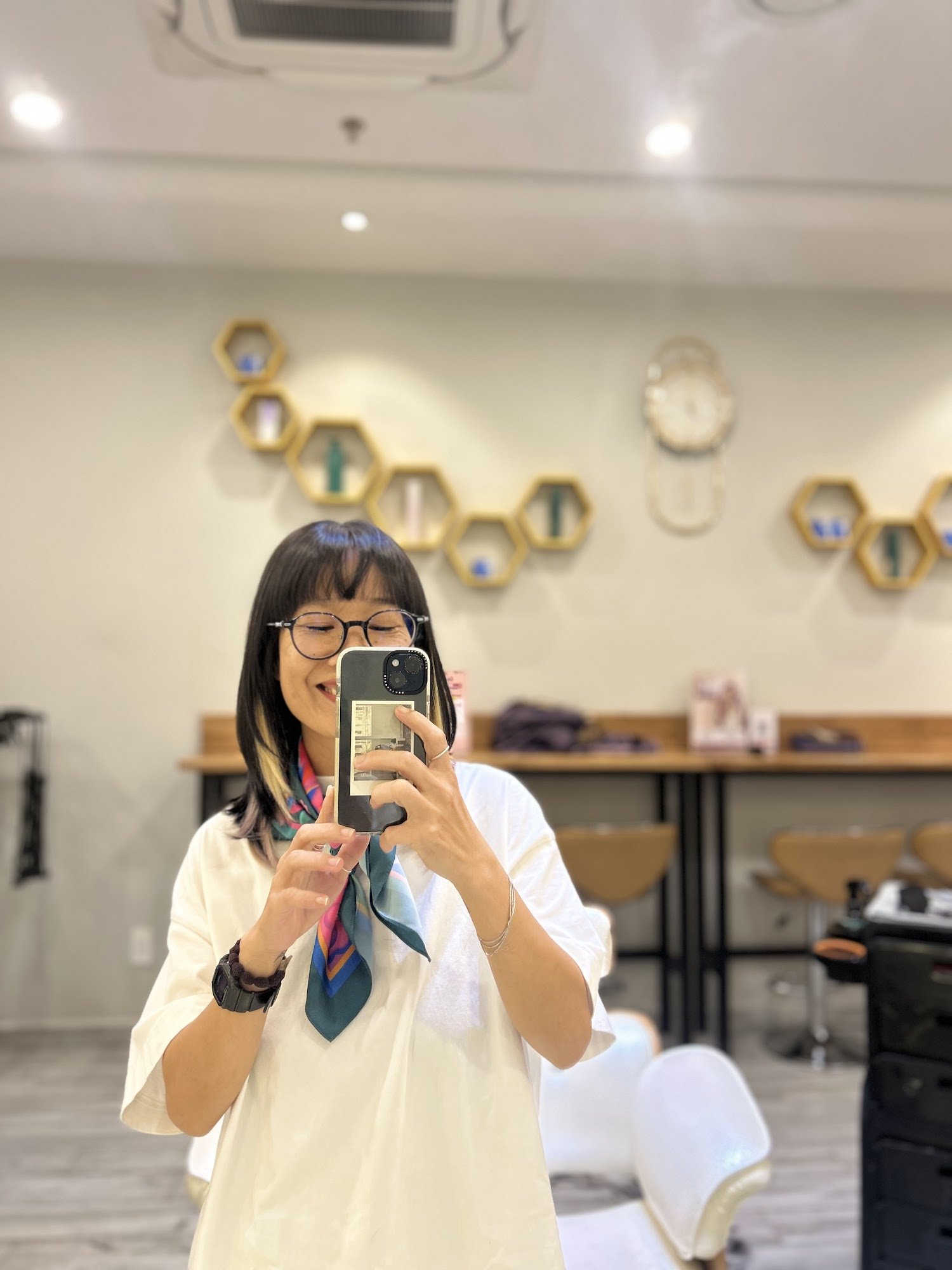 A woman is taking a selfie in what appears to be an interior space of a salon or barbershop.