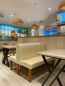 The image depicts the interior of a modern café or restaurant in Thao Dien, Saigon. It features beige upholstered booth seating with wooden frames, a 