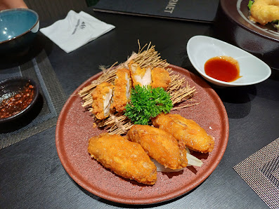 A plated dish consisting of golden-brown fried chicken pieces arranged on a red ceramic plate with garnishes including green herbs and possibly pickle