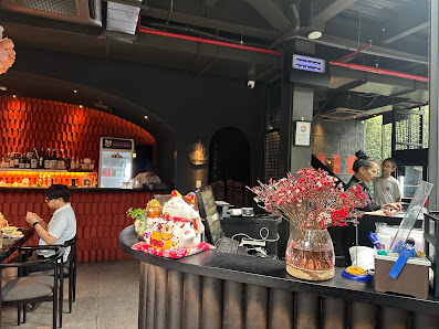 The image depicts the interior of a modern restaurant or bar in Thao Dien, Saigon. It features a black counter with a decorative arrangement including