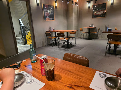 The image shows an interior view of a modern restaurant or cafe in Thao Dien, Saigon. The space is well-lit with warm lighting and features wooden tab